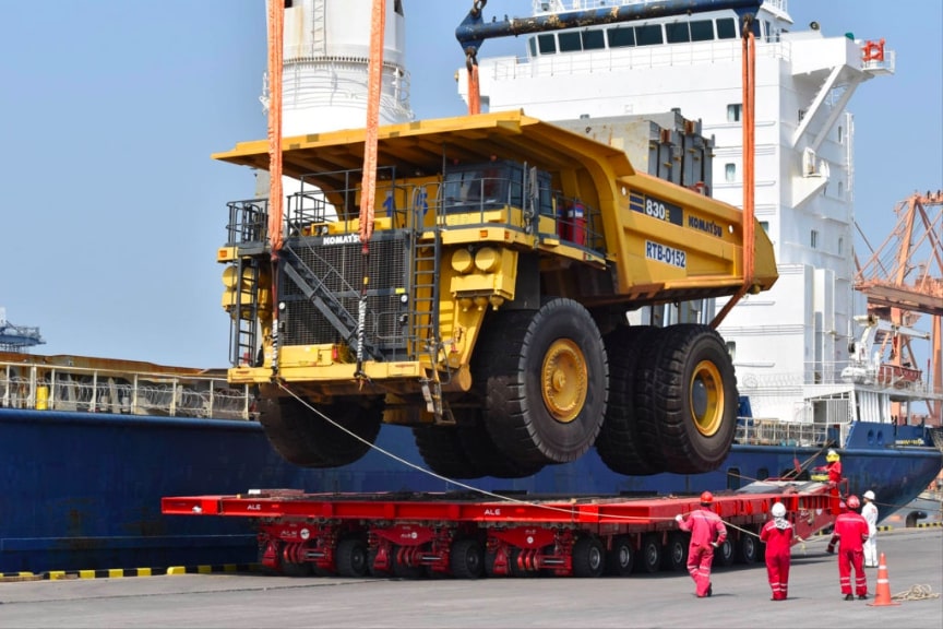 Crane loading mining machines from landing craft to vessel