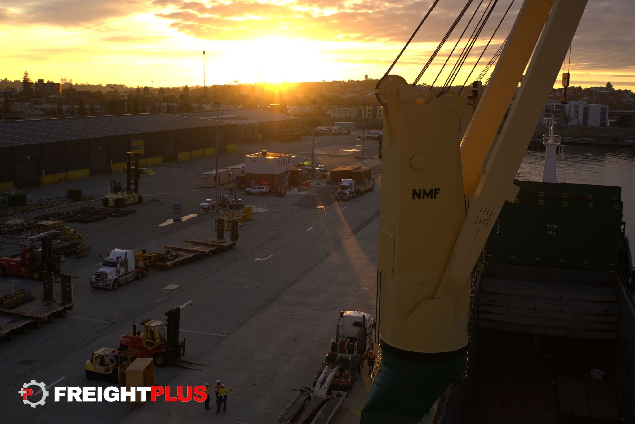 Yellow and green crane from a break bulk vessel in the foreground of a sunset at a Port.