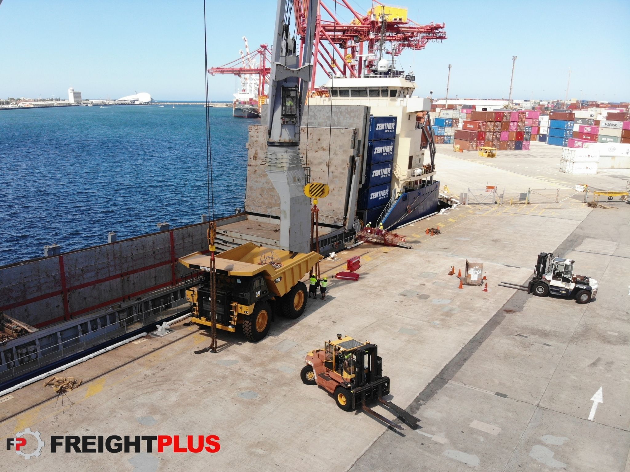 A Yellow Caterpillar Dump Trunk is being unloaded from a breakbulk vessel at a Port.