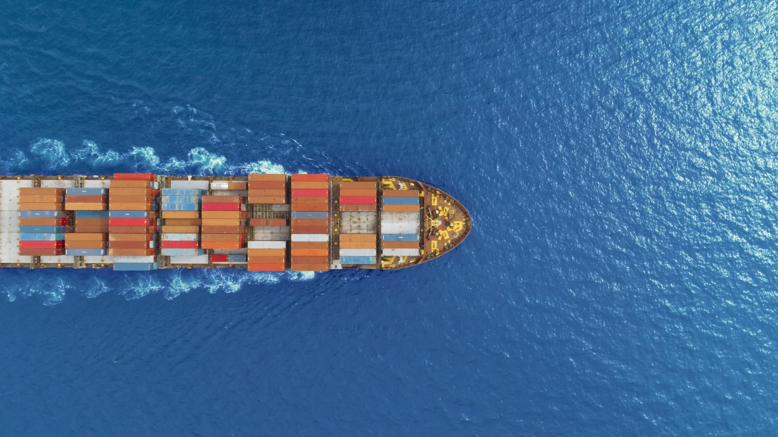 Birds eye view of container ship sailing smooth ocean.