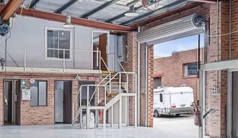 View of the first Freightplus office from inside a large warehouse, two stories tall. A large roller door stands open all the way.