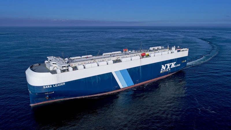 Shipping line, NYK Lines, Roll-on roll off vessel the Sara Leader sails on a flat deep blue sea.